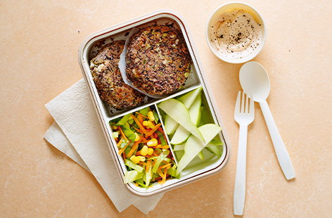 Now here's a lunchbox that'll be a real treat on a Friday! Juicy bean burgers are served with a crisp carrot and corn salad for a tasty veggie lunch