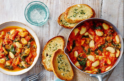 This colourful stew is filled out with creamy, chunky butter beans and wilted spinach leaves then served with garlic bread to mop up the tomato juices.