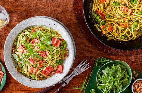 Peas are whizzed together with pine nuts, lemon, herbs and garlic to make a delicious vegan pesto, that is then tossed through spaghetti and topped with crispy pieces of meat-free smoky bacon for a deliciously green dinner!