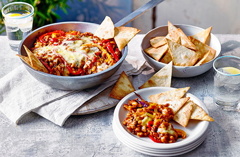 Give baked beans a twist with this spicy Mexican beans recipe. Add fajita seasoning and sweet softened peppers to your beans then top with cheese and bake until bubbling – serve with easy homemade tortilla chips and dig in!