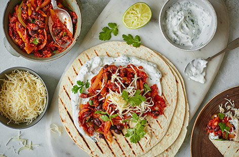 Go Mexican for dinner tonight with this veggie bean fajita recipe. Make a smoky paprika-spiced black bean mixture with peppers and onions, then let everyone load up their own tortillas and top with cheese, yogurt and coriander.