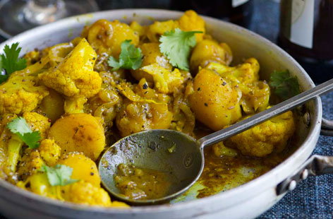 A vegetarian Indian dish consisting of various spices, potatoes and cauliflower