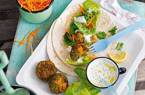 Falafel don't have to always be made with chickpeas, as this recipe with sweet potatoes and peas demonstrates. Seasoned with ground cumin, coriander and fresh, finely chopped coriander and parsley, the falafel are baked then served in tortillas with a garlic yoghurt sauce.