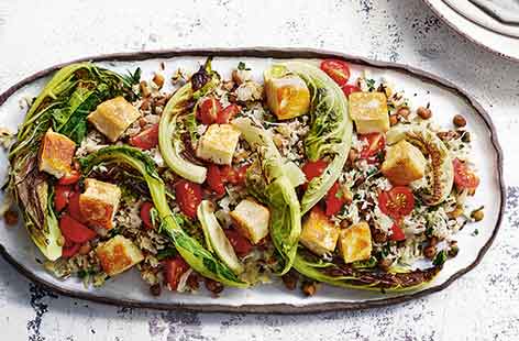 Think again before throwing away the leaves of a cauliflower. Sprinkled with oil and quickly roasted, cauliflower leaves become deliciously crispy and ensure nothing is wasted. Golden fried halloumi, tomatoes and plenty of fresh herbs finish this hearty ve