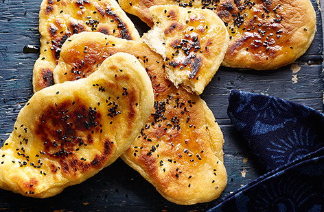 Serve up these homemade naan breads as part of a delicious weekend Indian feast. Warm and fluffy, this naan bread recipe is finished with a sprinkling of aromatic nigella seeds and can be served with a drizzle of spicy chilli oil, if liked. 