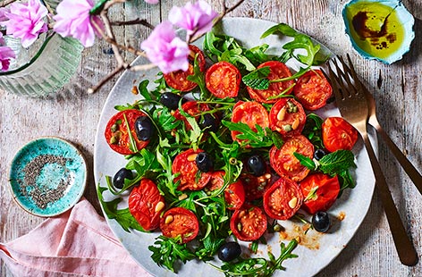 Slow-roasting results in sweet, sticky, intensely flavoured tomatoes that are delicious in this punchy Mediterranean salad of rocket, olive, capers and pine nuts. This technique is also handy if you're hosting a crowd as there's very little hands-on effort