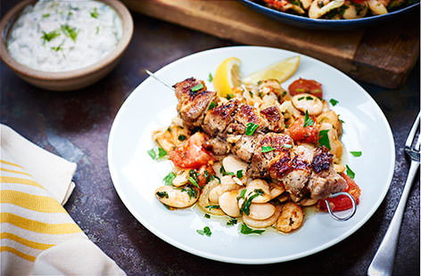 Rustle up some authentic Greek souvlaki for the ultimate fakeaway. Succulent pork belly is marinated in lemon, oregano, bay leaf and garlic, served with fragrant butter beans and creamy tzatziki.  